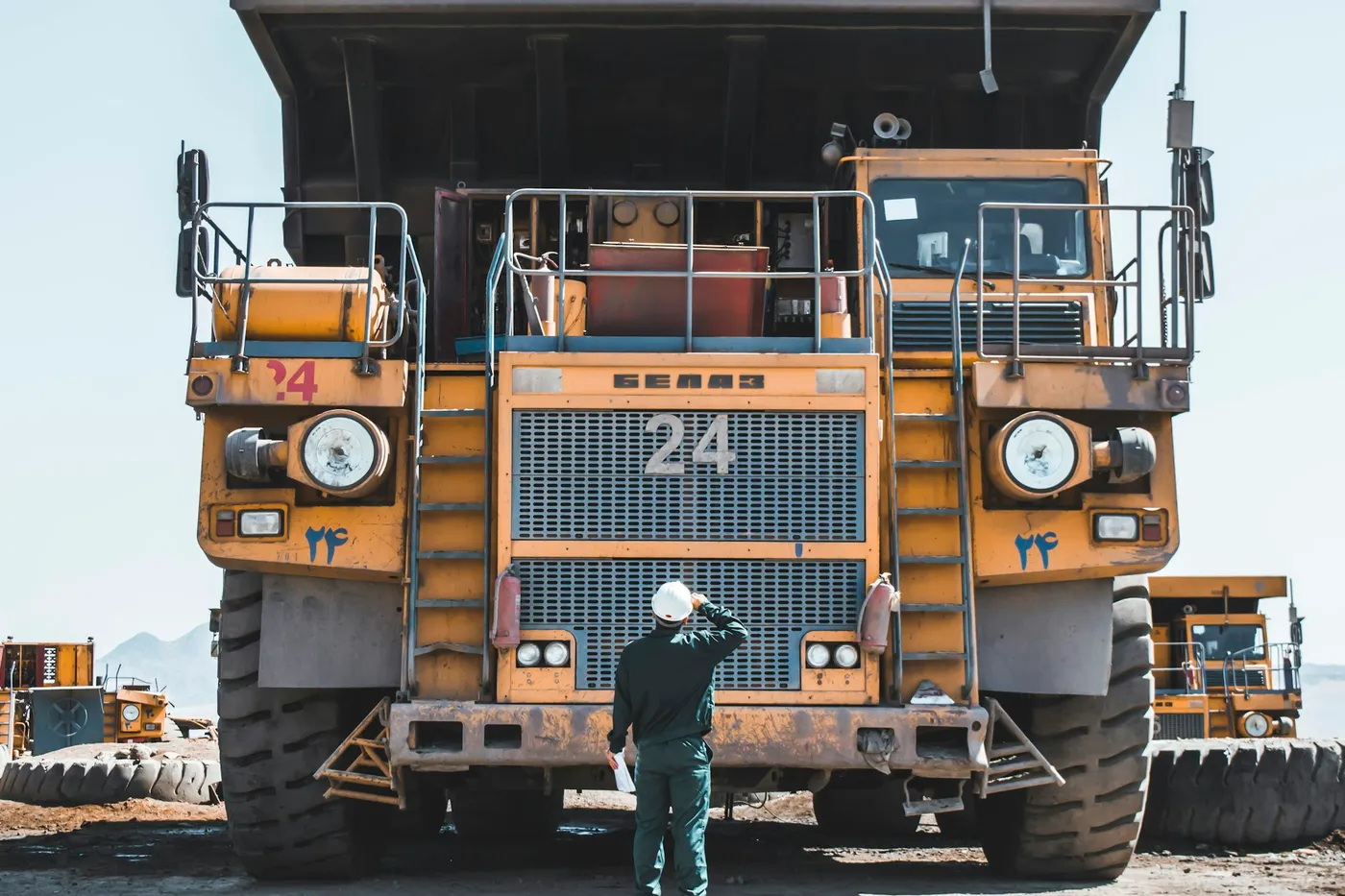 A worker standing in front of a line of haul trucks